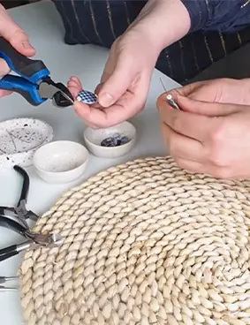 les mains de deux personnes en train de réaliser des bijoux lors d'un atelier upcycling