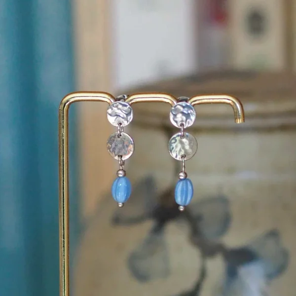 une paire de boucles d'oreilles upcyclées argentées et bleues sur un portant