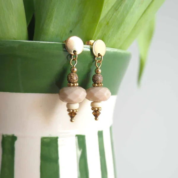 Des boucles d'oreilles upcyclées marrons accrochées au bord d'un vase