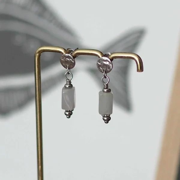 une paire de boucles d'oreilles argentées avec des pierres grises de seconde main sur un portant