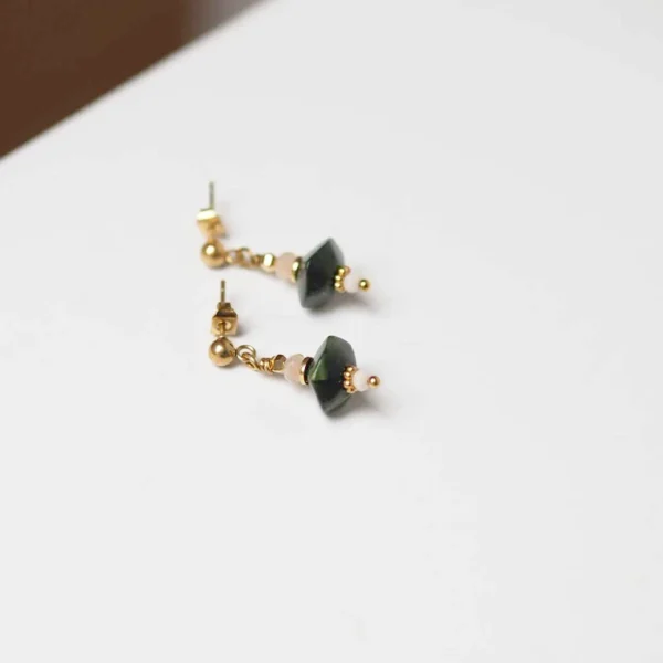 des boucles d'oreilles upcyclées kaki et rose pâle à plat sur un fond blanc
