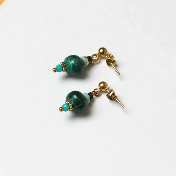 une paire de boucles d'oreilles upcyclées avec des perles en malachite de seconde main à plat sur fond blanc