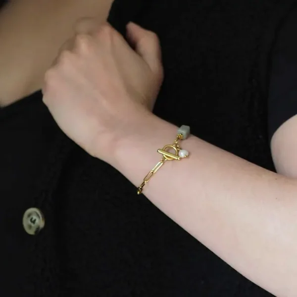 un bras de femme qui porte à son poignet un bracelet upcyclé doré qui se ferme sur le devant
