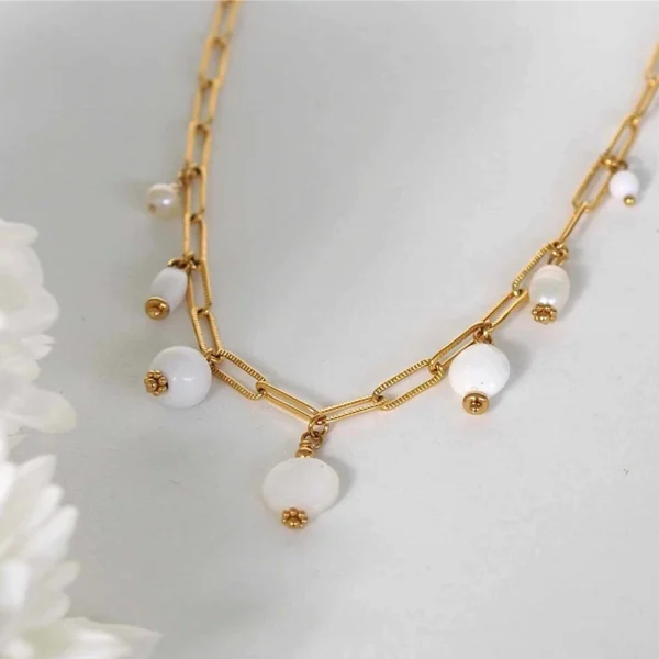 un collier upcyclé composé de sept perles blanches montées en breloques sur une chaîne en acier inoxydable mailles trombones dorée