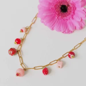 un collier upcyclé composé de perles roses et rouges de seconde main montées en breloques sur une chaîne en acier inoxydable mailles trombones dorée