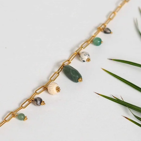 un collier upcyclé composé de perles vertes, écrues et grises de seconde main montées en breloques sur une chaîne en acier inoxydable mailles trombones dorée