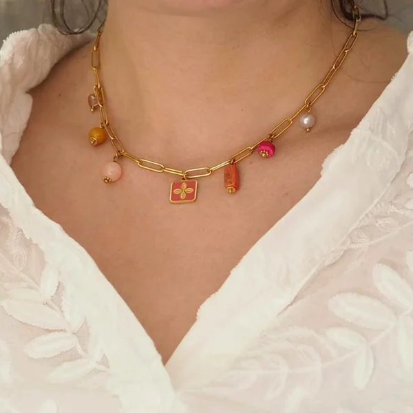 un cou de femme portant un collier upcyclé avec une chaîne en acier inoxydable dorée et des perles dans les tons chauds de seconde main montées en breloques