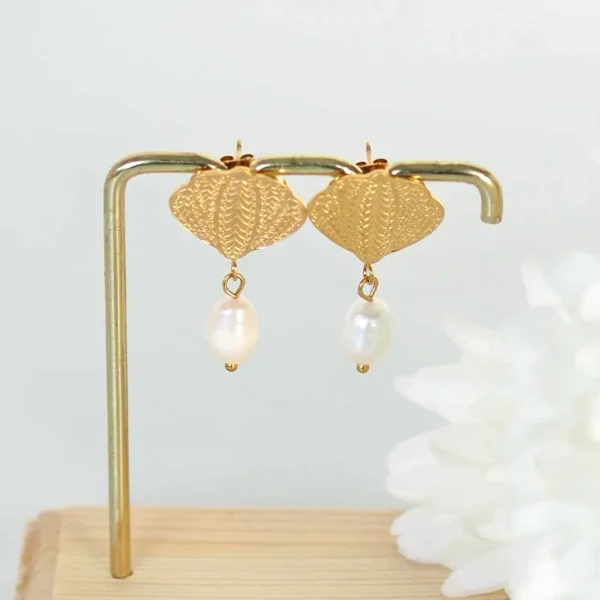 boucles d'oreilles upcyclées avec des montures coquillages et des perles d'eau douce de seconde main sur un portant