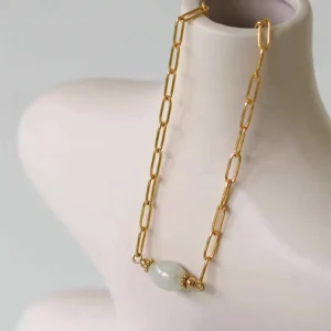 collier upcyclé avec une pierre au centre posé sur un vase beige